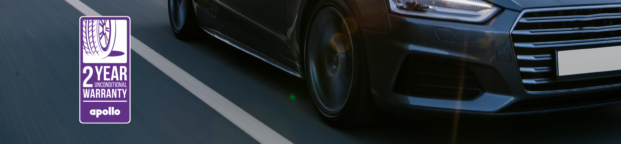 apollo warranty: a black car driving down the road with focus on the tyres.